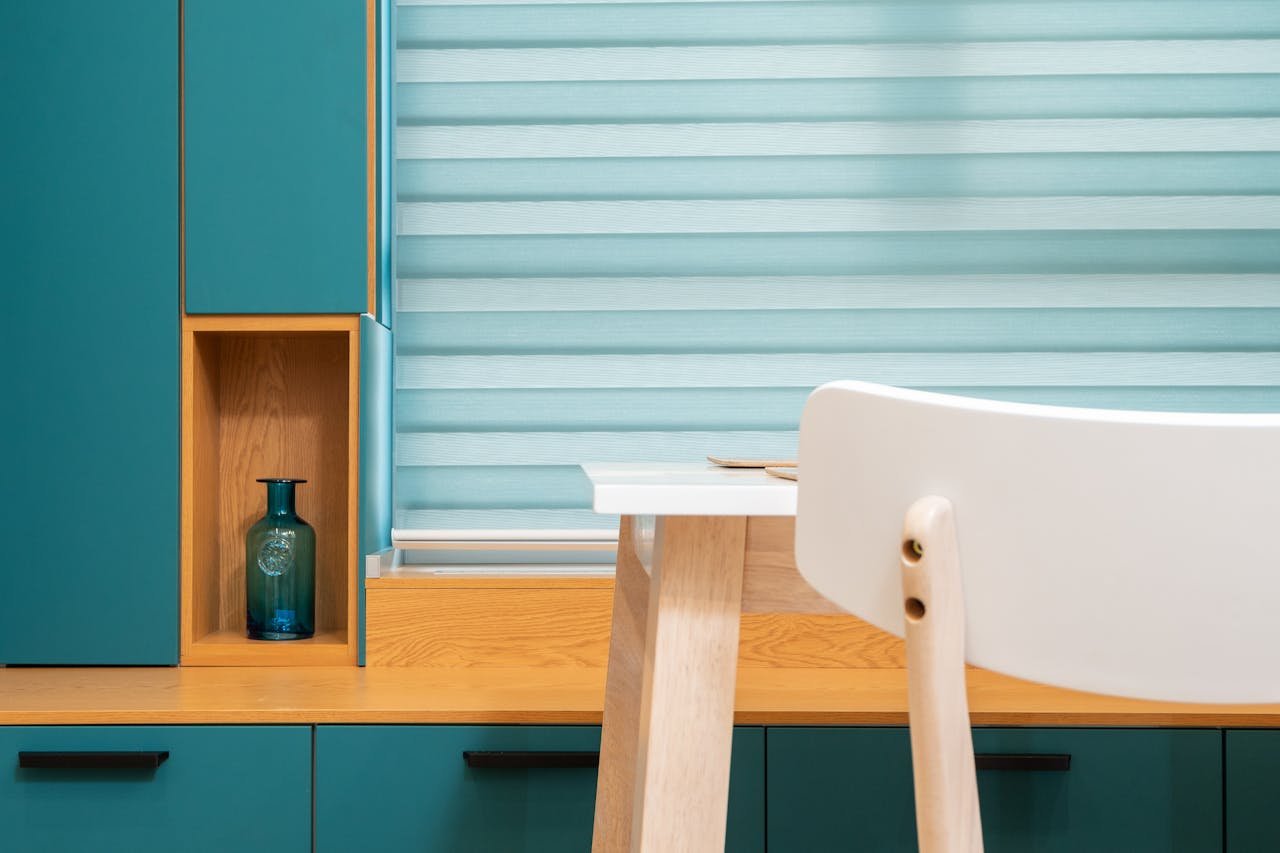A modern interior featuring turquoise cabinets, a white chair, and wooden elements in a minimalist style.